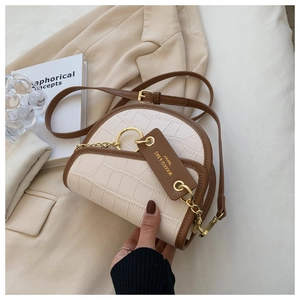 Detail of cream and brown saddle bag with crocodile texture and gold chain decoration