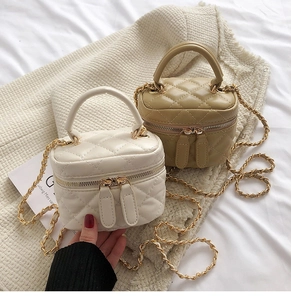 Detail of cream and khaki quilted mini bucket bags with chain straps on magazine
