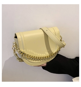 Detail view of cream saddle bag with decorative gold chain and adjustable leather strap