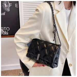 Detail of black quilted leather shoulder bag with metallic chain and gold ball charm
