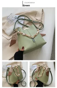 Detail of light green bucket bag featuring a gold chain and floral scarf decoration