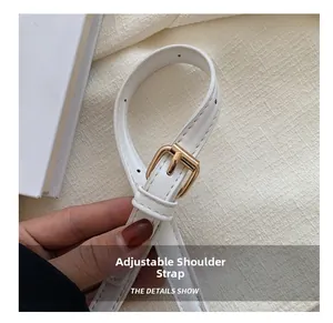 Detailed view of adjustable white leather shoulder strap with gold metal buckle