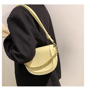 Detail of light yellow saddle bag with gold chain strap on black blazer model