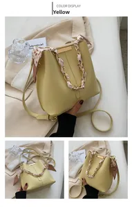 Detail of yellow bucket bag featuring a silk scarf gold chain and premium leather texture