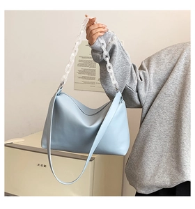 Detail of light blue crossbody bag featuring a trendy clear acrylic chain and leather strap