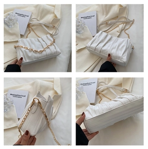 Detail view of white ruched shoulder bag showing gold chain strap and magnetic closure