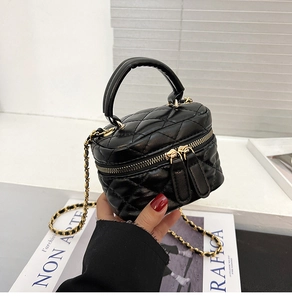 Close-up of black quilted leather mini vanity bag with gold chain strap and top handle