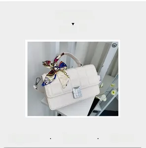 Detail of cream quilted handbag with silver square lock and decorative floral scarf handle