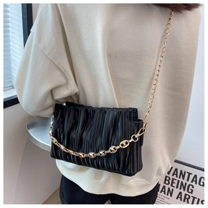 Detail of black pleated cloud bag with decorative gold chunky chain and shoulder strap