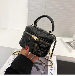 Detail of a black quilted mini handbag with gold chain strap and top handle