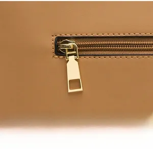 Detail of smooth golden metal zipper on light brown litchi pattern leather handbag