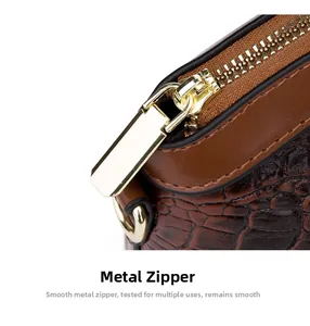 Detail of smooth gold zipper and crocodile texture on dark brown leather handbag