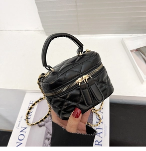 Detail of black quilted leather mini vanity bag with gold chain and dual zippers