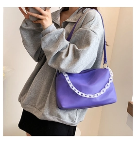 Detail view of purple matte shoulder bag with chunky white acrylic chain and strap