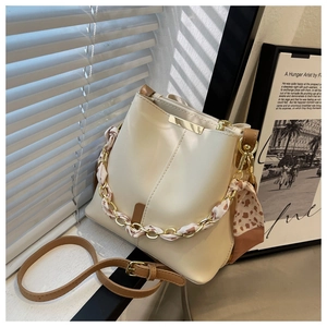 Detail of cream bucket bag with silk scarf chain handle and cross-body strap