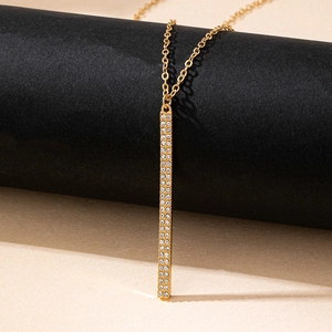Collier à pendentif barre dorée avec strass pavés présenté sur un support noir