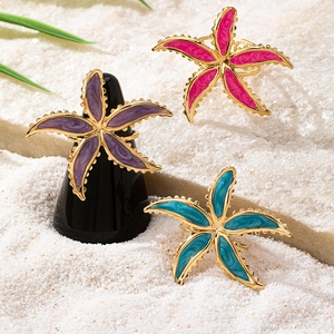 Three-piece starfish ring set with colorful enamel detail on white beach sand