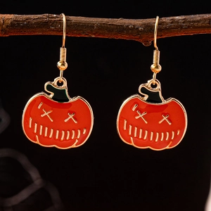 Close-up of Halloween pumpkin earrings with gold hooks on a natural branch setup