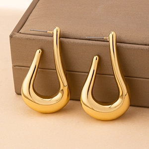 Détail des boucles d'oreilles créoles dorées polies sur un coffret à bijoux texturé