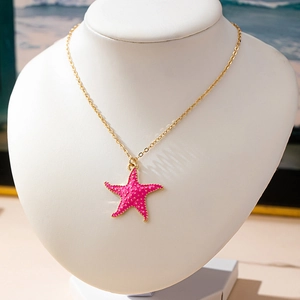 Detail of a bright fuchsia starfish pendant necklace with golden sea skin texture