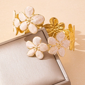 Elegant gold metal open arm cuff featuring cream and coffee enamel floral patterns