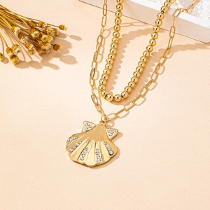 Detail of a gold-plated double-layer necklace with a crystal-encrusted scallop pendant
