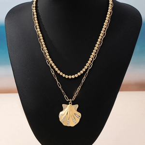 Golden double-layered shell pendant necklace with bead and paperclip chain on a black bust