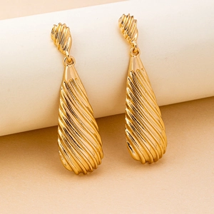 Close-up of golden teardrop earrings featuring elegant spiral textures and metallic finish
