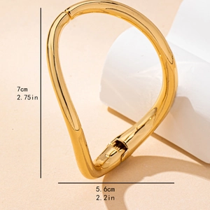 Minimalist irregular twisted gold bangle with mirror finish and dimensions 7cm by 5.6cm