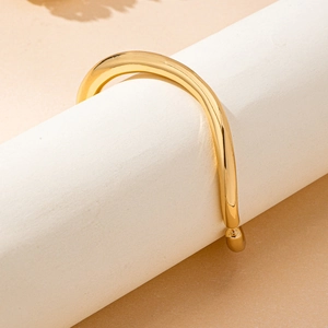 Minimalist gold-plated open tube bracelet with polished sphere ends on a white stand