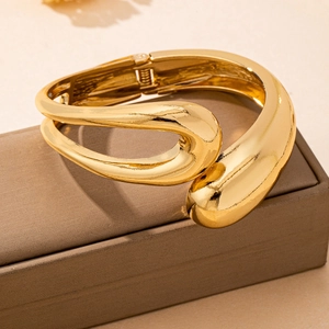 Close-up of a gold geometric cuff bracelet with a polished finish and hinge closure