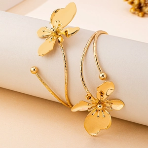 Elegant gold flower open bangle bracelet with textured band on a minimalist display