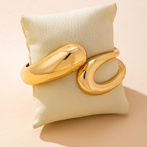 Minimalist adjustable gold teardrop cuff bracelet with a polished mirror finish on pillow