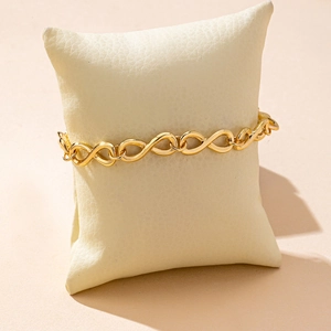 Detailed view of infinity link gold-plated bracelet on a premium beige display cushion