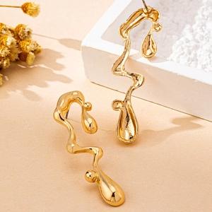 Gold irregular lava-style earrings with a polished metallic finish on a display stand