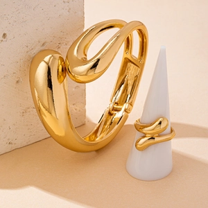 Detail of minimalist gold organic shape bracelet and ring set with fluid metallic curves