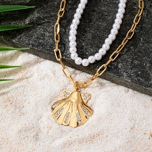 Collier double rang avec pendentif coquillage et perles sur fond de sable