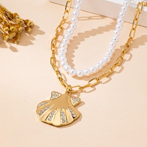 Détail du collier double couche doré avec pendentif coquillage et perles blanches