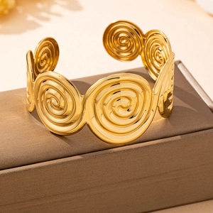 Detail of a polished gold geometric spiral cuff bracelet on a premium display stand