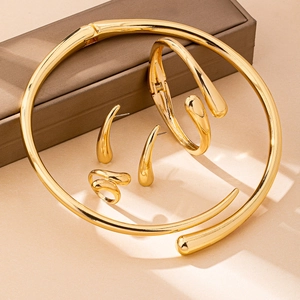 Detail of a polished gold jewelry set featuring minimalist ring and curved necklace