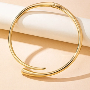 Macro detail of high-polish gold metal choker necklace with tapered overlap design