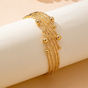 Elegant multi-layered gold bracelet featuring textured coils and polished sphere accents