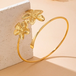 Detailed shot of golden dual-flower open arm cuff with delicate petal texture