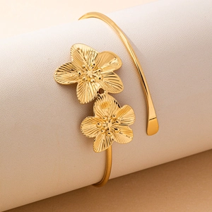 Elegant gold open arm cuff featuring two three-dimensional textured flower petals