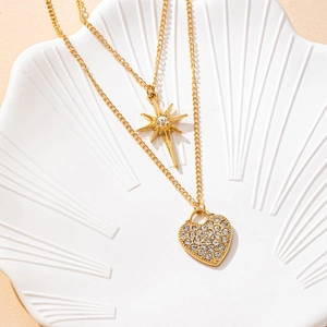 Double-layered gold necklace featuring an octagonal star and rhinestone heart pendant
