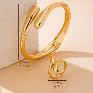 Polished gold minimalist open bangle and wrap ring set on artistic stone background