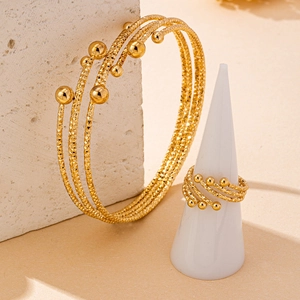 Detailed view of gold bracelet and ring with diamond-cut texture on minimalist stone display