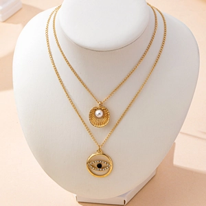 Close-up of double layer gold necklace with shell pearl and crystal evil eye pendant