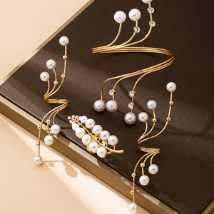 Dettaglio del set di gioielli con perle, ear cuff dorati e bracciale rigido elegante