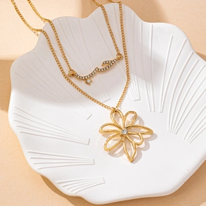 Collier double couche doré avec pendentif fleur et cristaux sur une coupelle en céramique